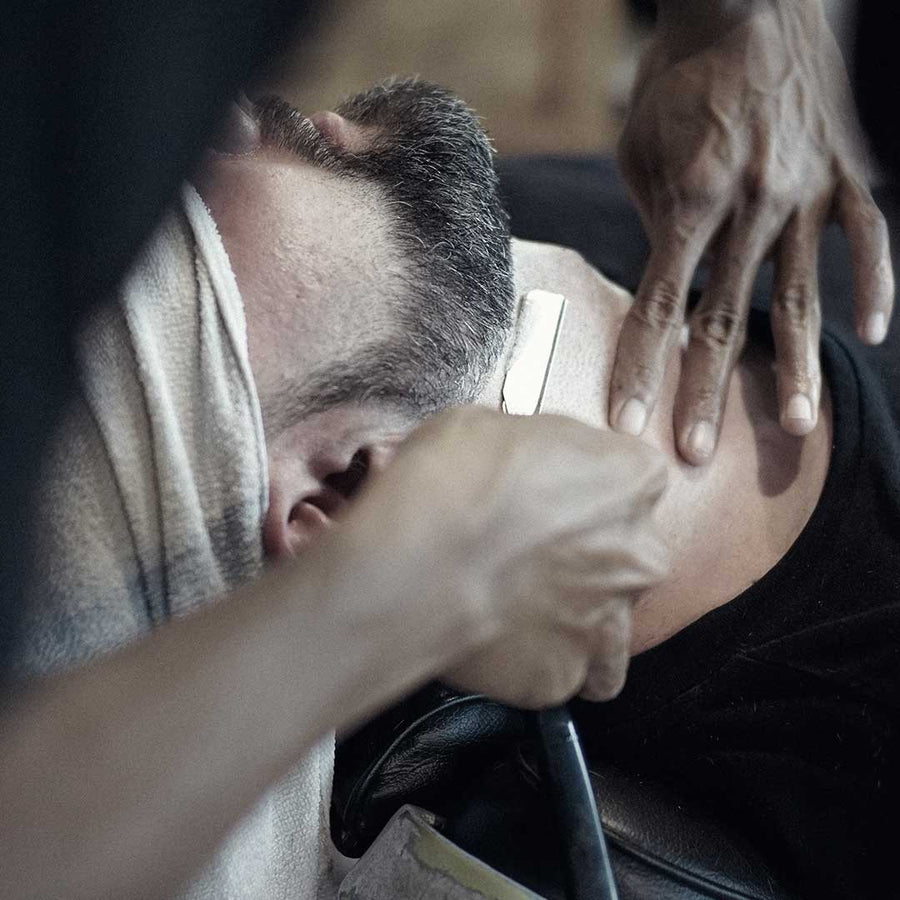 Barber shaving a client with a straight razor